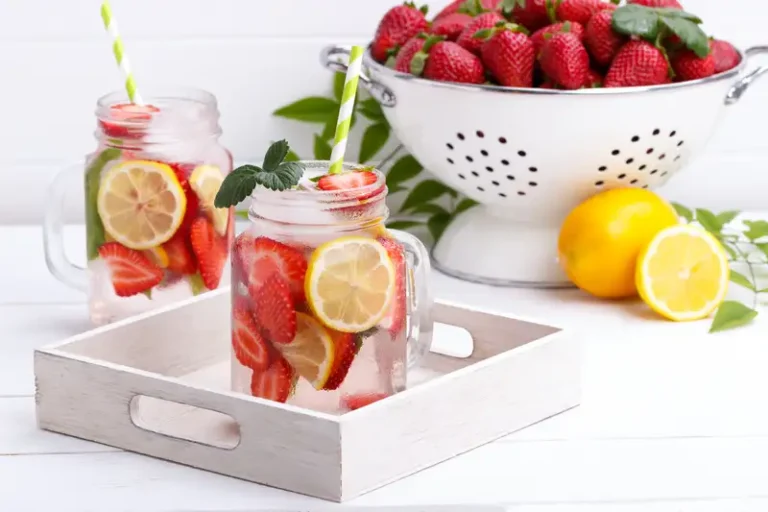 Air infus buah dalam gelas bening dengan irisan lemon, stroberi, dan daun mint, tampak segar dan menyehatkan.