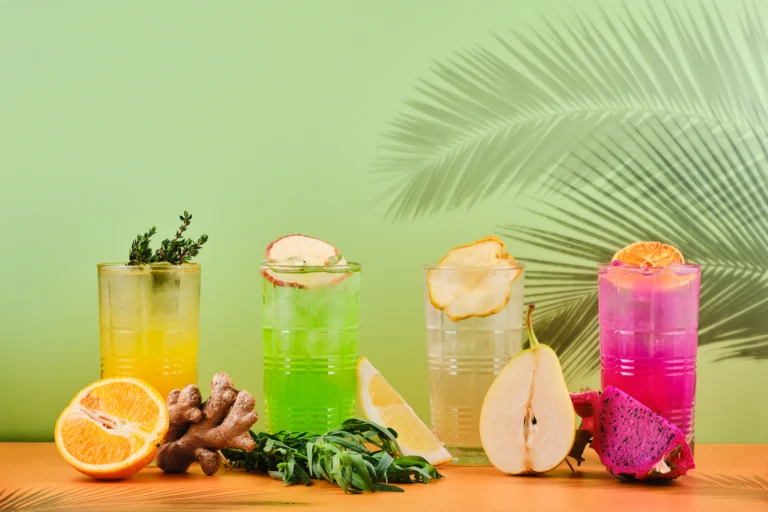 Dua gelas tinggi berisi minuman dingin dengan irisan lemon dan es, disajikan segar di atas meja.