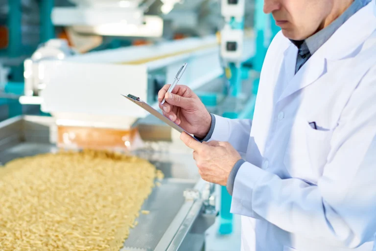 Petugas quality control mencatat hasil inspeksi di area produksi pabrik pangan dan minuman.