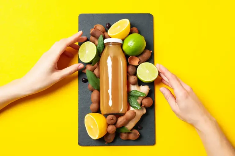 Segelas jus asam jawa manis segar dengan es batu, disajikan sebagai minuman herbal vegan yang menyegarkan.