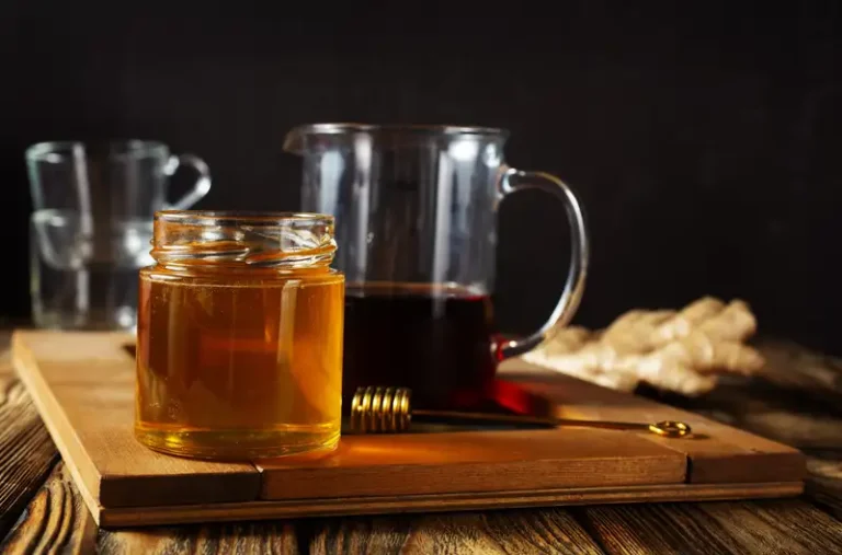 Madu dan jahe segar tersaji di meja kayu, menggambarkan bahan alami minuman penambah stamina.