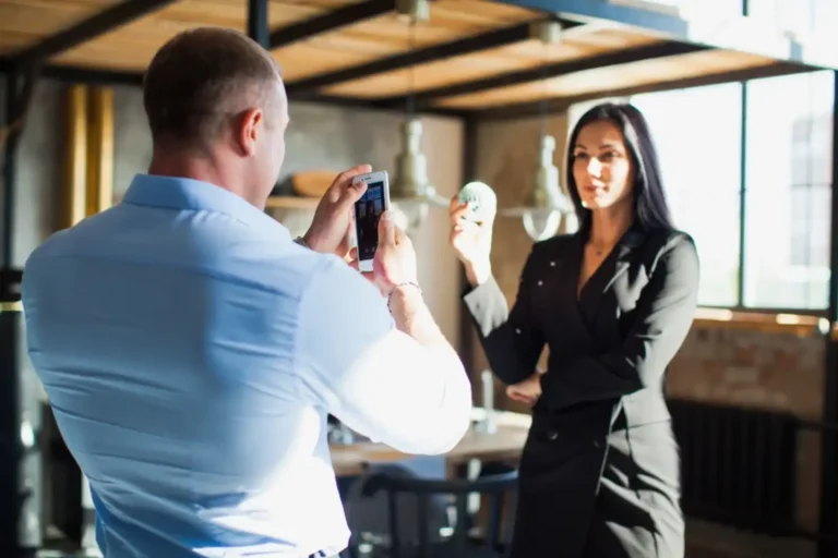 Pasangan saling memotret dengan ponsel di luar ruangan, mencerminkan pembuatan konten untuk branding bisnis.