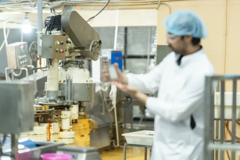 Inspektor memeriksa mesin otomatis di lini produksi makanan untuk memastikan proses pengolahan berjalan baik