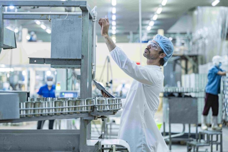 Tim berdiskusi sambil meninjau dokumen dan sampel produk di meja dalam suasana kerja industri maklon.