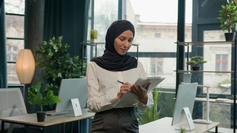 Perempuan muslim berhijab tersenyum ceria, menggambarkan semangat dan optimisme dalam menjalankan usaha.