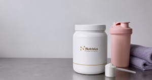Botol suplemen creatine wanita dengan shaker merah muda di rak retail bersih.