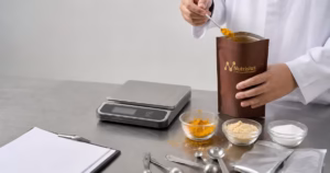 Teknolog pangan membandingkan campuran bumbu terukur untuk standarisasi resep franchise di meja stainless.