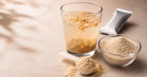 Minuman serbuk tidak larut sempurna: gumpalan mengambang di permukaan dan endapan menumpuk di dasar gelas, di samping sachet dan mangkuk bubuk.